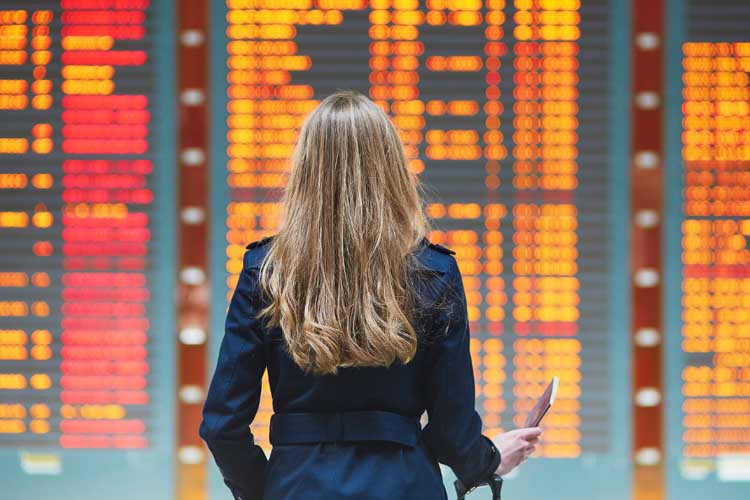 Kobieta patrząca na tablicę odlotów na lotnisku