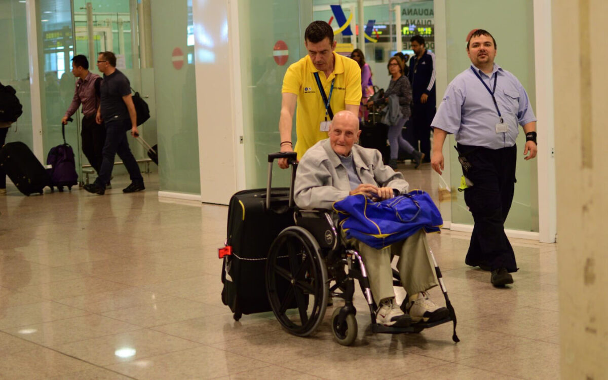 obsługa lotniskowa pomaga mężczyźnie z niepełnosprawnością dostać się na odprawę